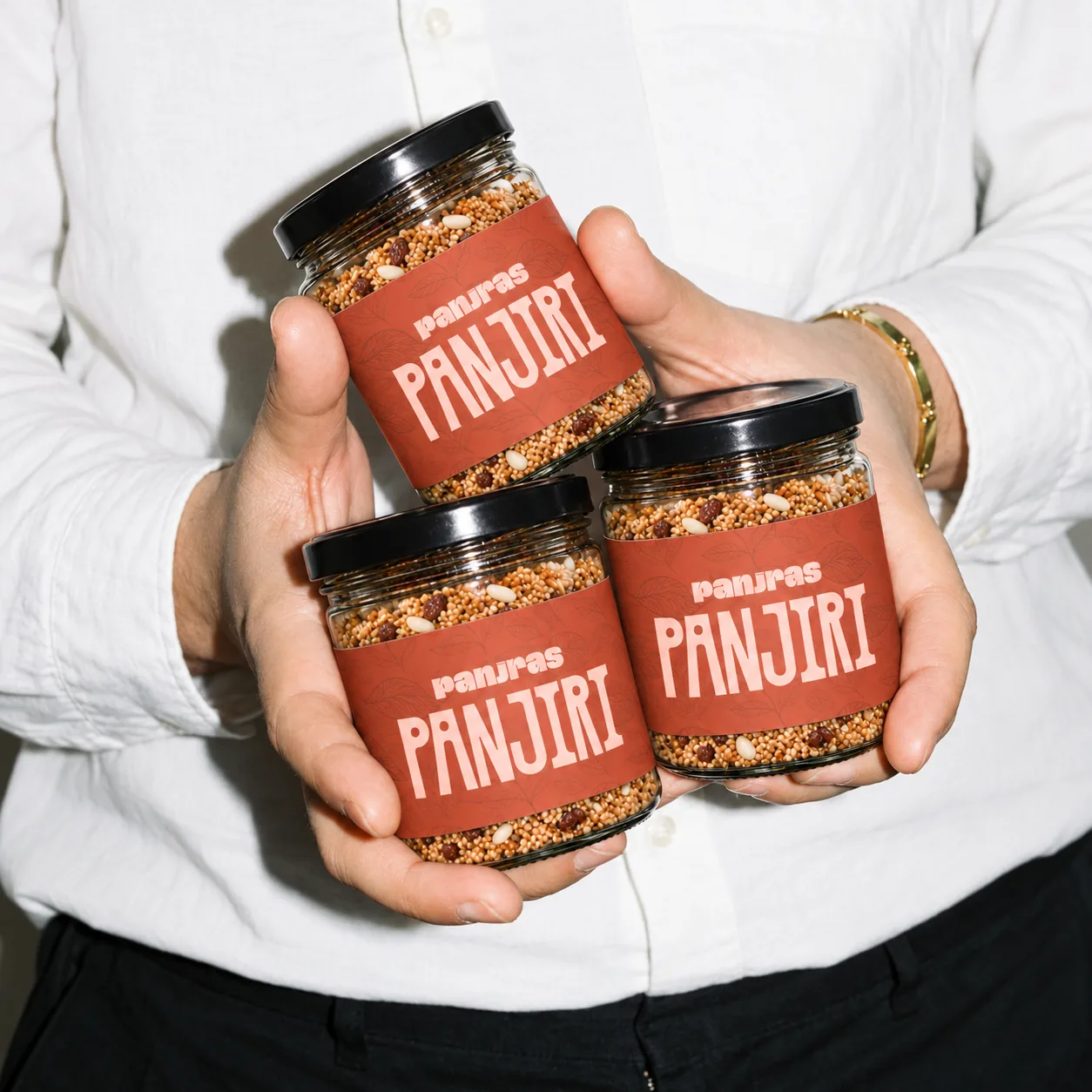 Three jars of PanjRas Panjiri held in two hands