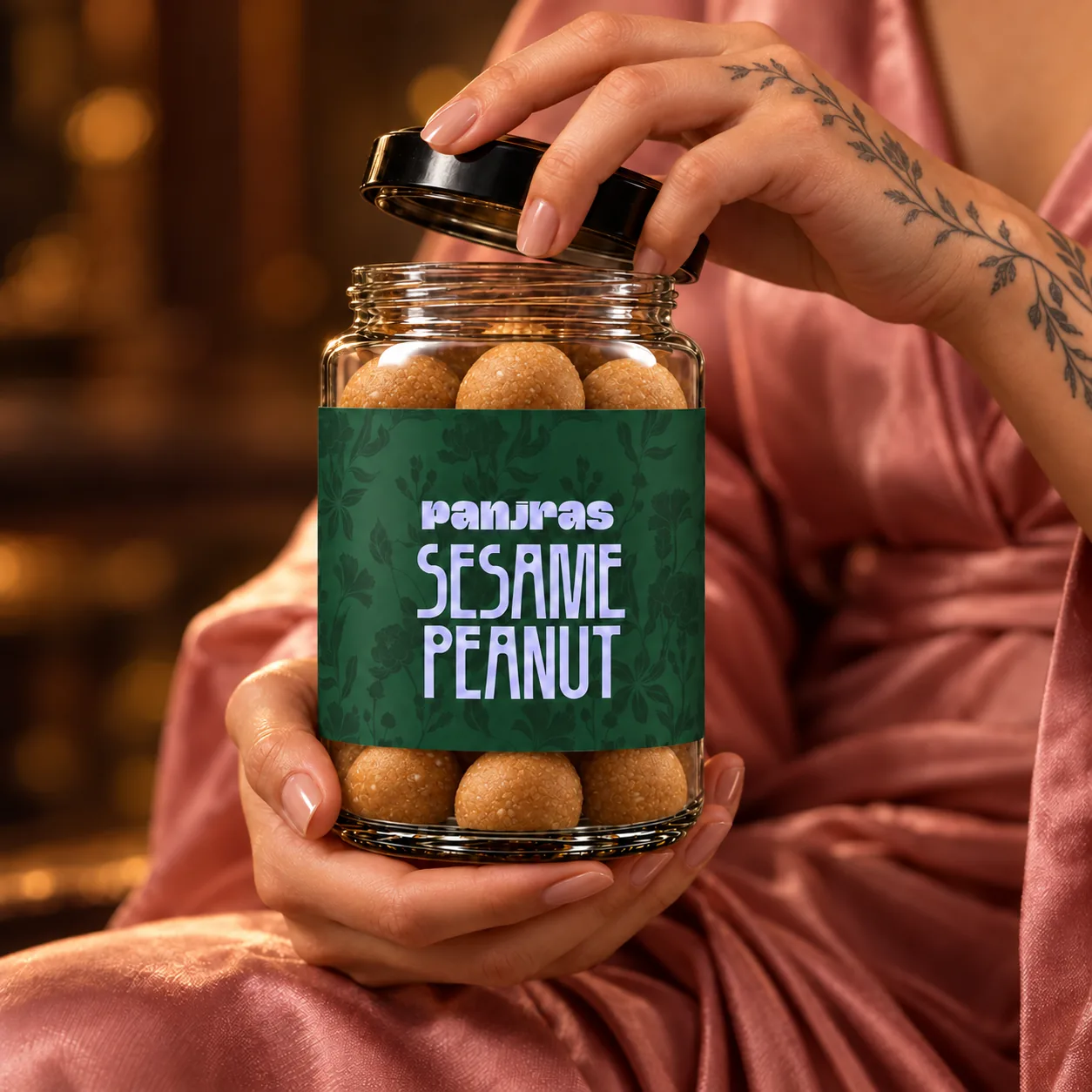 Hands opening a PanjRas jar of sesame peanut ladoos